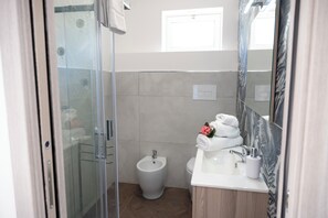 A modern bathroom with a glass shower enclosure, a bidet, a sink with a mirror, and a towel rack. - Villa Verde- Nature Holiday Home (Carini)