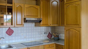 A kitchen with wooden cabinets, a stainless steel sink, and a tiled backsplash. - Casa Vacanze Alessio (Nusco)