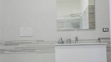 A modern bathroom with a toilet, bidet, sink, and mirror.