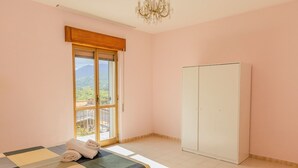 A bedroom with a bed, a wardrobe, and a window with a view of greenery. - Casa Vacanze Alessio (Nusco)