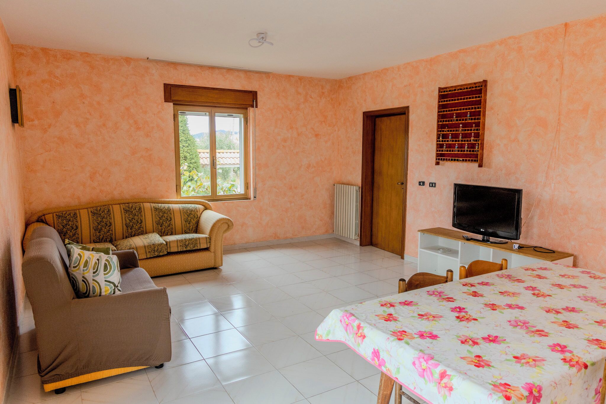 A room with a sofa, a TV, a bed, and a window.