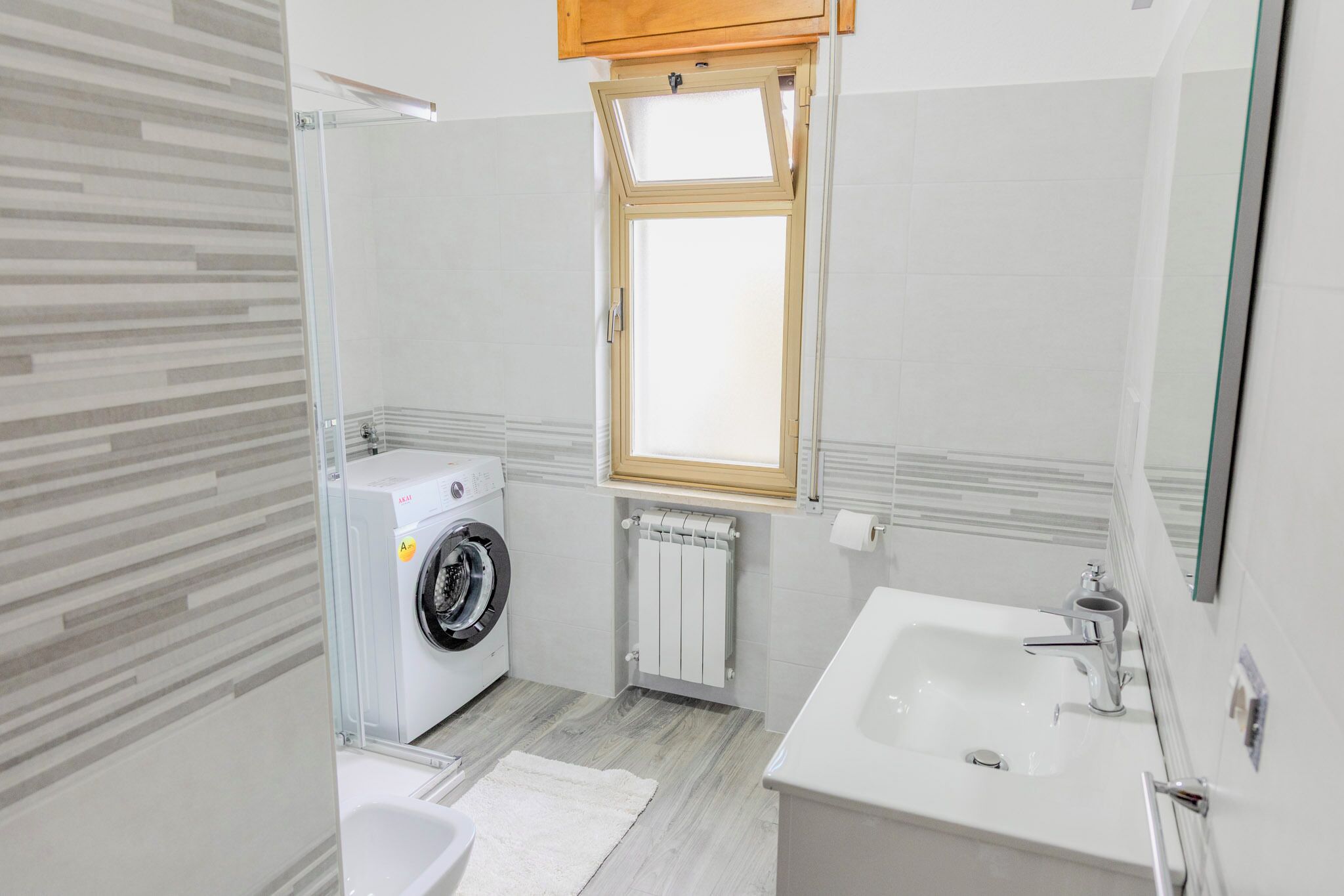 A compact bathroom with a washing machine, a sink, and a window.