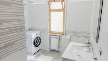 A compact bathroom with a washing machine, a sink, and a window.