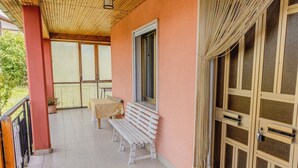 A covered balcony with a bench, a table, and a door with a mesh screen. - Casa Vacanze Alessio (Nusco)