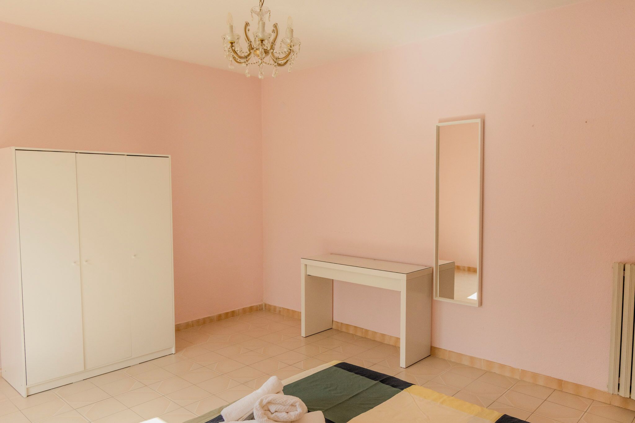 Una habitación con armario, escritorio, espejo y candelabro.