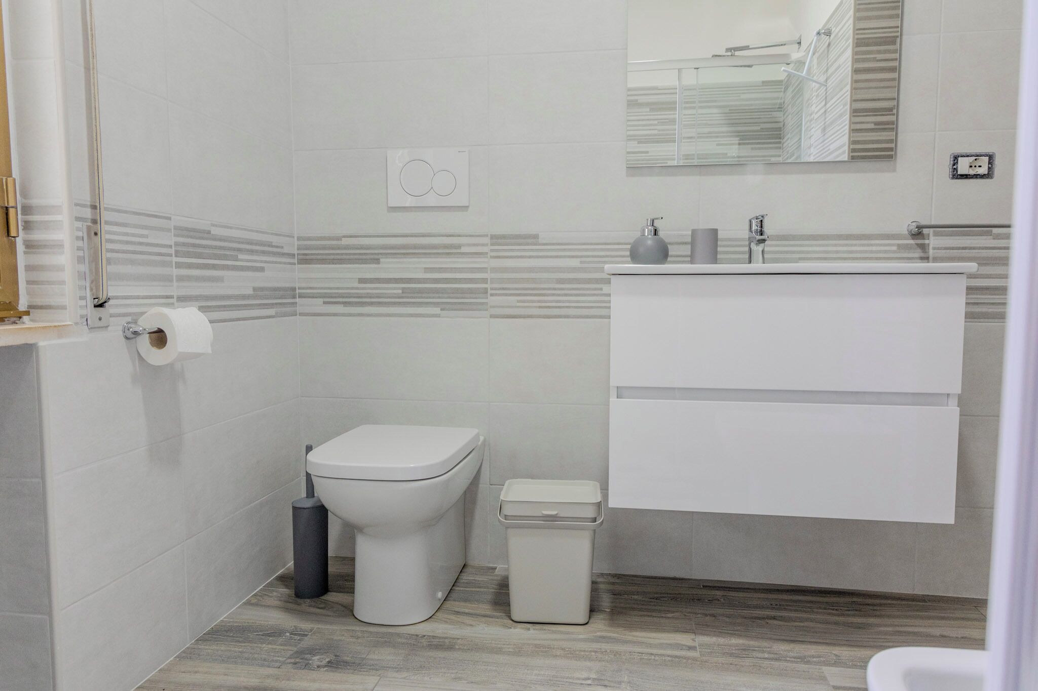 A modern bathroom with a toilet, bidet, and a sink with a mirror above.
