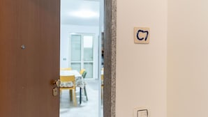 A room with a wooden door, a wall-mounted light switch, and a small sign with the number 7. - Cariddi (Caulonia)