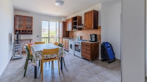 A compact kitchen with wooden cabinets, a washing machine, and a dining area with a table and chairs. - Cariddi (Caulonia)