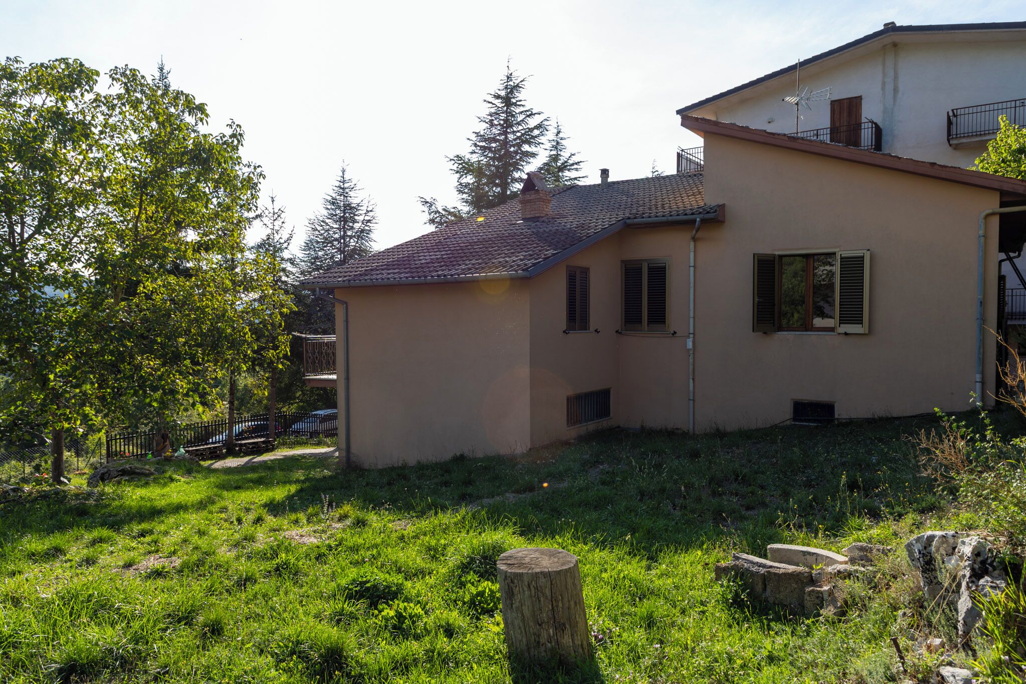 Une maison à deux étages, avec un toit en pente, une cheminée bien visible et une petite fenêtre avec des volets.