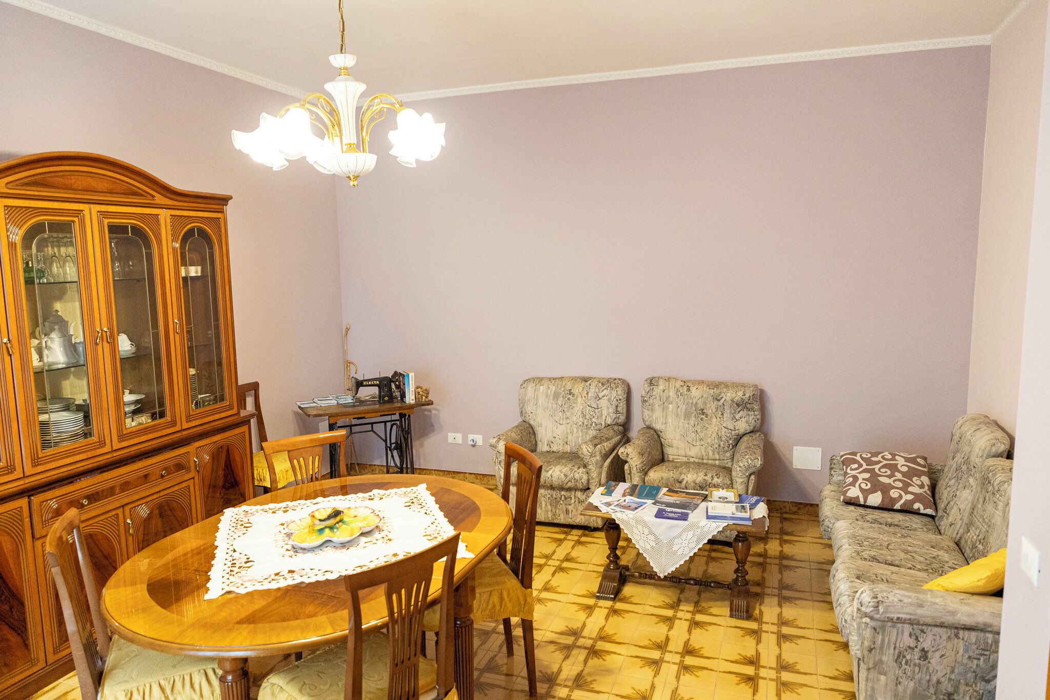 Un comedor con mesa de madera, sillas, un armario y un sofá estampado.