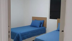 A room with two single beds, each with a wooden headboard and blue bedding. - Beautiful House in Maceió - 5 minutes from the Airport - 24-hour Check-in (Maceió)