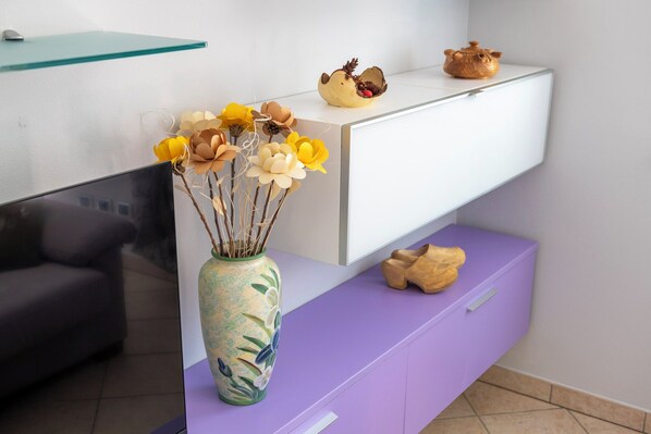 A modern reception area with a white desk, a purple cabinet, and a vase with dried flowers. - La Maison De L'Adret (Saint-Pierre)