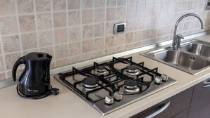 A kitchen with a gas stove, a coffee maker, and a sink. - La Maison De L'Adret (Saint-Pierre)