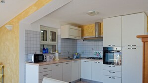 A compact kitchen with white cabinets, a microwave, a stove, and a sink. - Mermaid - Cala Gonone (Cala Gonone)