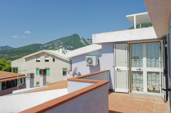 A residential building with a white exterior, a tiled roof, and a balcony with a red-tiled edge. - Mermaid - Cala Gonone (Cala Gonone)