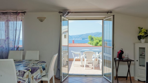 A balcony with a table and chairs, a small cabinet, and a view of the sea. - Mermaid - Cala Gonone (Cala Gonone)