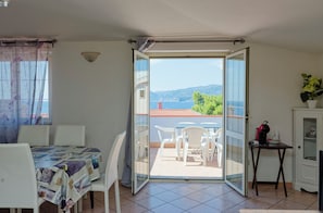 A balcony with a table and chairs, a small cabinet, and a view of the sea. - Mermaid - Cala Gonone (Cala Gonone)
