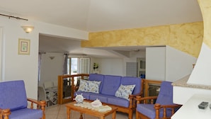 A living room with a blue sofa, wooden chairs, a coffee table, and a white cabinet. - Mermaid - Cala Gonone (Cala Gonone)