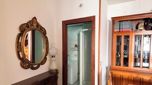 Una habitación con un armario de madera, un espejo, una mesa de comedor con mantel individual estampado y un aparador con libros.