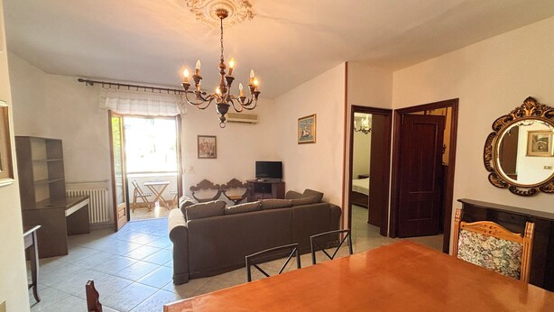 Una sala de estar con sofá, mesa de comedor y televisor.