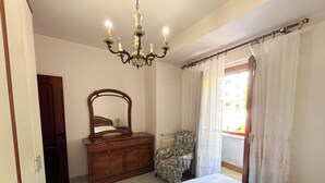 Un dormitorio con cama, cómoda, silla y candelabro.