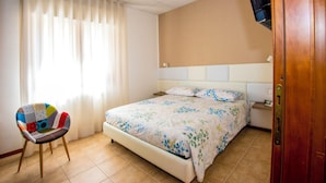 Ein Schlafzimmer mit einem Bett, einem Sessel, einem Fernseher und einer Tür.