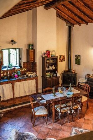 A traditional kitchen with a dining area, wooden furniture, and a fireplace. - Vigna Dell'Etna (Piedimonte Etneo)