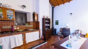 Een keuken met een betegelde spatwand, houten keukenkastjes en een eethoek met een tafel gedekt voor twee personen.