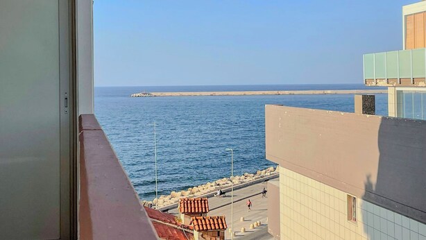 A view from a balcony overlooking a coastal area with a clear sky, a sandy beach, and a calm sea. - Mora Suite (Bari)
