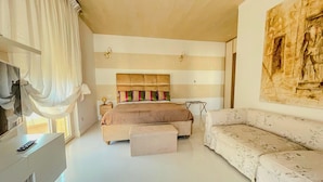 A bedroom with a large bed, a sofa, a desk, and a painting on the wall. - Mora Suite (Bari)