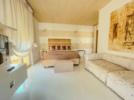 Una camera da letto con un letto grande, un divano, una scrivania e un quadro appeso al muro.
