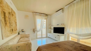 A bedroom with a large bed, a sofa, a TV, and a painting on the wall. - Mora Suite (Bari)