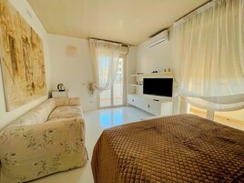 Una camera da letto con un letto grande, un divano, una TV e un quadro appeso al muro.