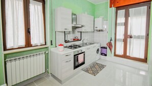 A compact kitchen with a gas stove, oven, sink, and a washing machine. - Casa Ida (San Giovanni Rotondo)