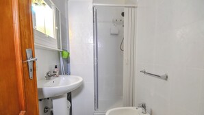 A bathroom with a wooden door, a white sink, a toilet, and a glass-enclosed shower. - Casa Ida (San Giovanni Rotondo)