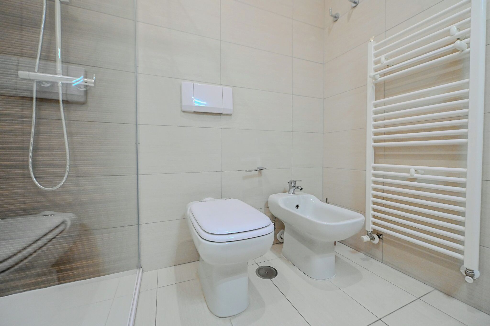 A modern bathroom with a toilet, bidet, and a shower.