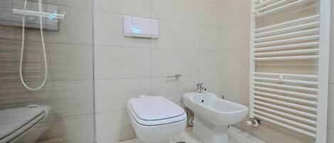 A modern bathroom with a toilet, bidet, and a shower.