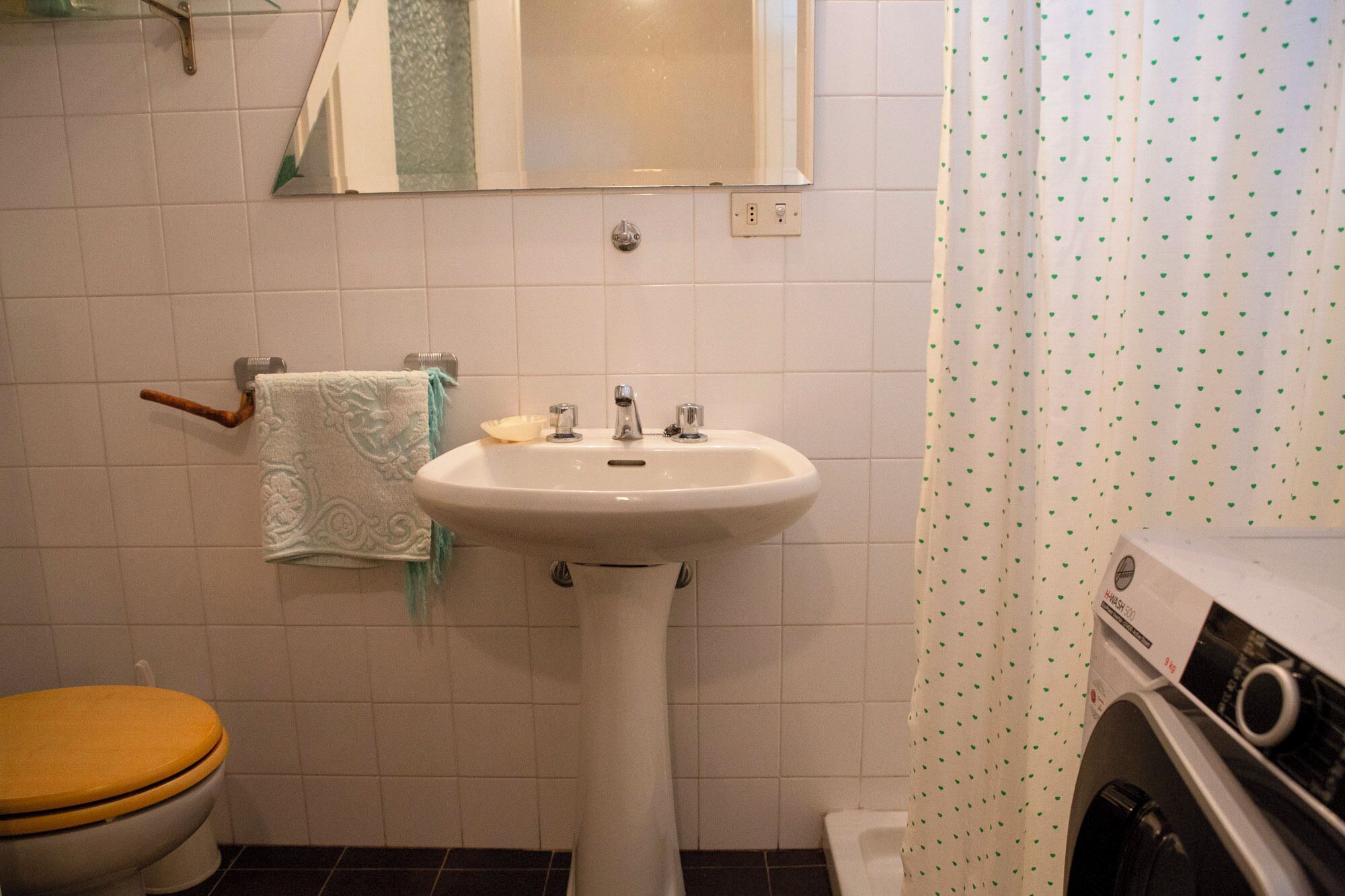 A bathroom with a white sink, a towel rack with a towel, a toilet, and a washing machine.