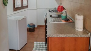 Cozinha compacta com geladeira, fogão a gás e um pequeno balcão.
