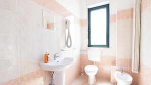 Une salle de bain équipée d’un lavabo, de toilettes, d’un bidet et d’un miroir.