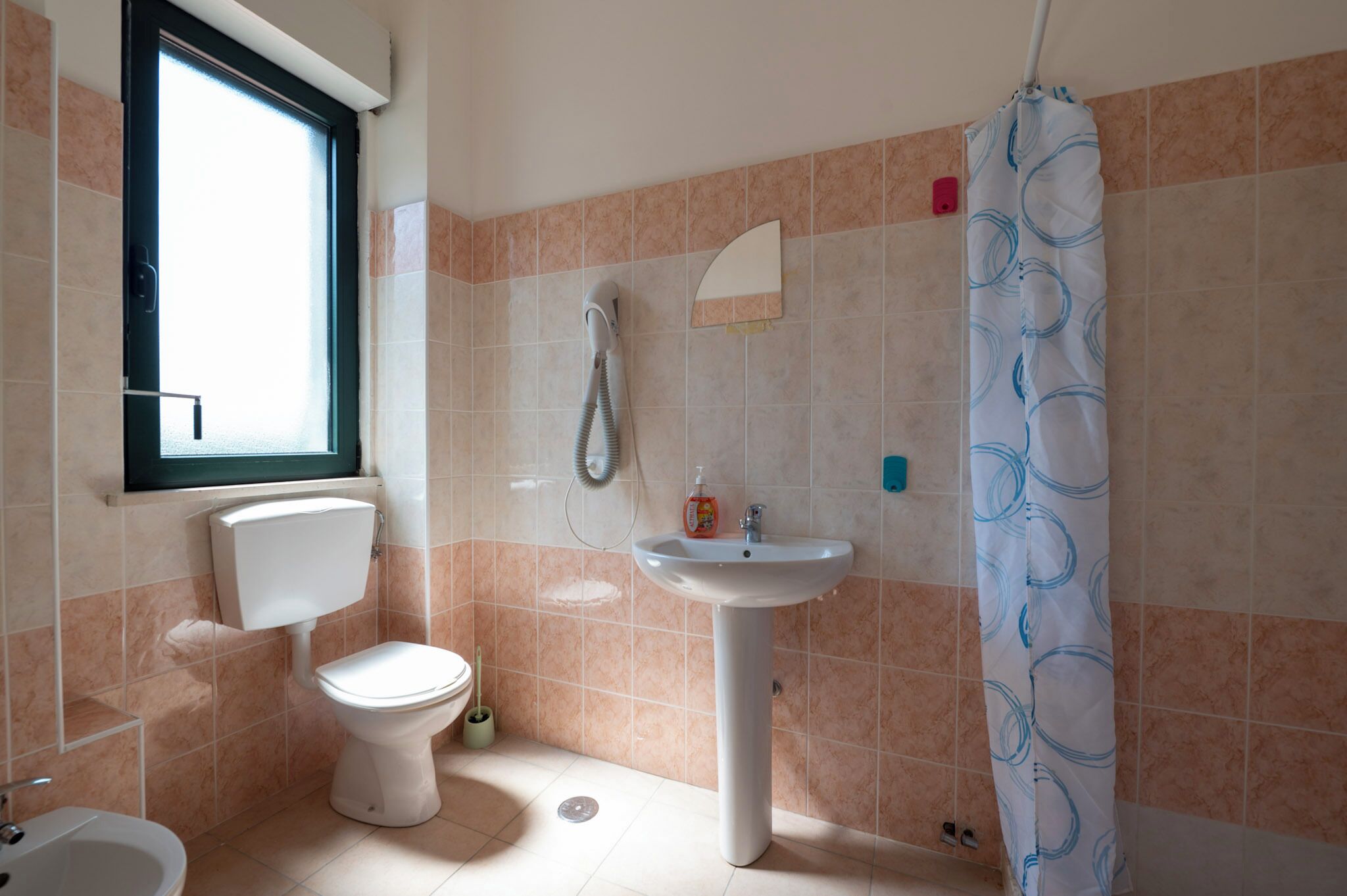 Une salle de bain avec des toilettes, un lavabo et un rideau de douche.