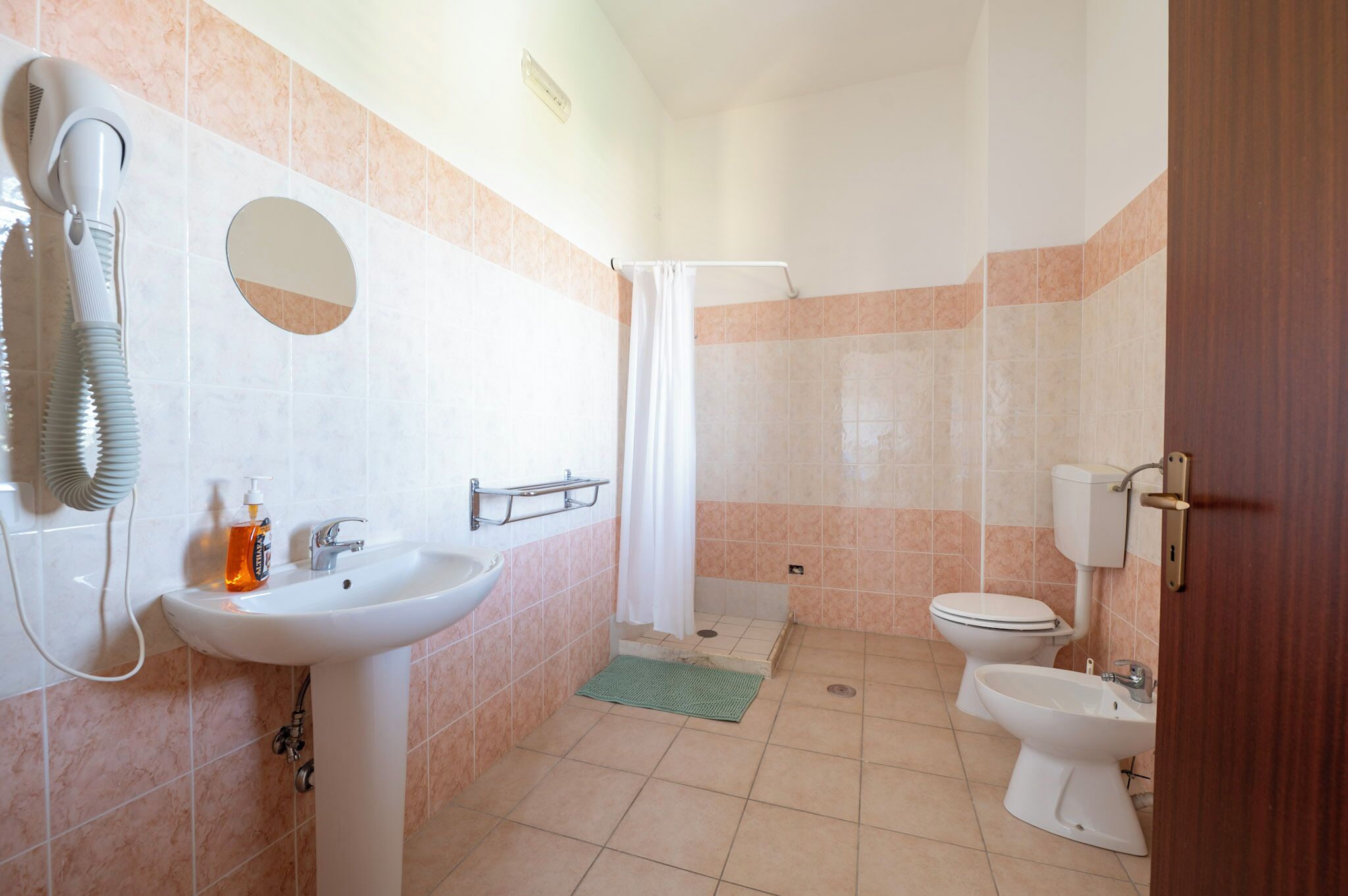 Ein Badezimmer mit Waschbecken, Toilette, Bidet und Duschvorhang.