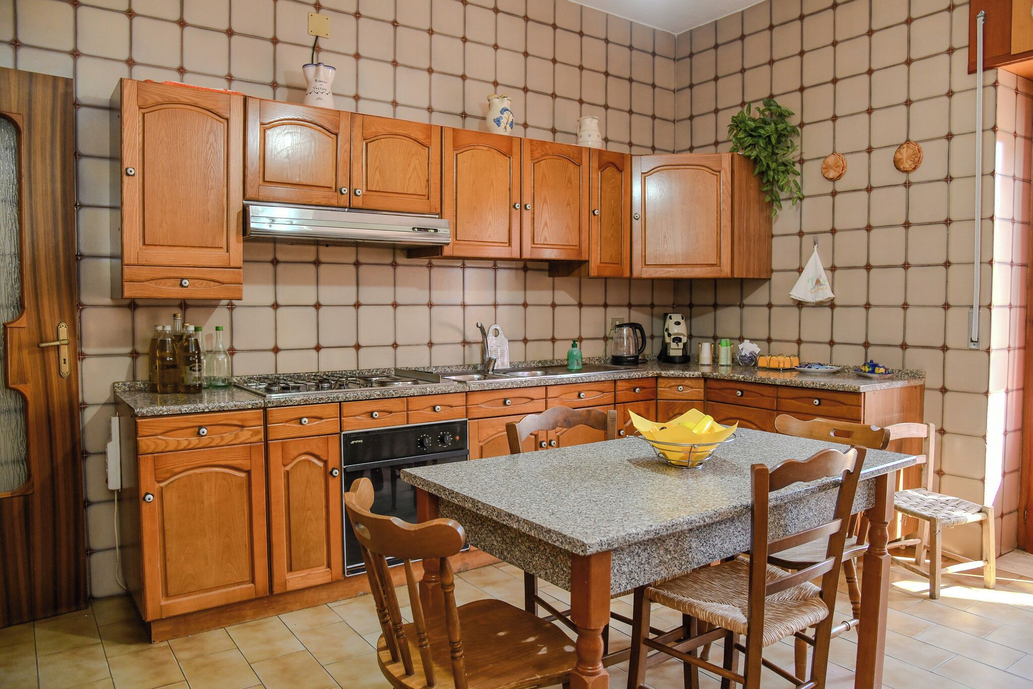 Una cocina con armarios de madera, encimera de granito, estufa y una mesa de comedor con sillas.