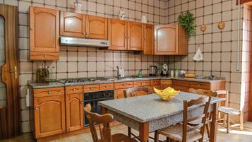 Una cocina con armarios de madera, encimera de granito, estufa y una mesa de comedor con sillas.