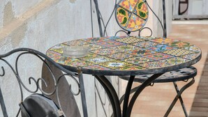 A metal table and chair with a colorful mosaic tabletop, positioned on a tiled patio. - Le Sciosce (San Giorgio Lucano)