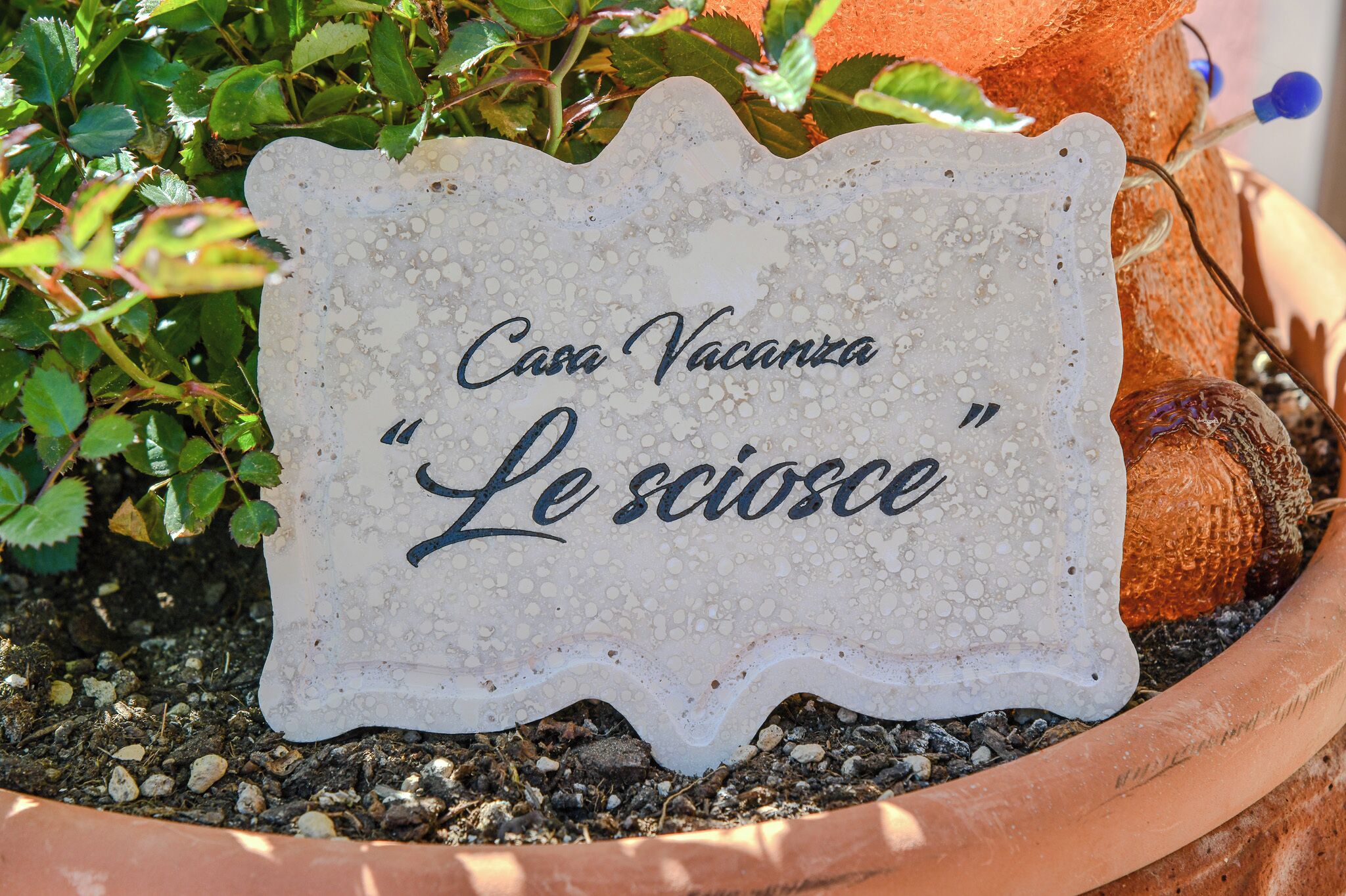 A sign with the text 'Casa Vacanza Le sciosce' in a terracotta pot.