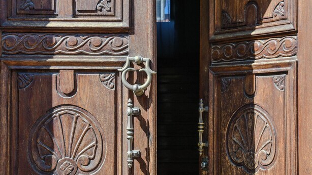 A wooden door with intricate carvings and a brass handle. - Le Sciosce (San Giorgio Lucano)