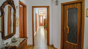 A hallway with wooden doors, a mirror, a dresser, and a potted plant. - Le Sciosce (San Giorgio Lucano)