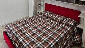 A bedroom with a bed, a red headboard, a white wardrobe, and a circular light fixture. - Sonech (Sonico)