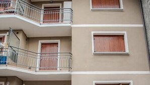 A multi-story building with balconies and a parked white car. - Sonech (Sonico)